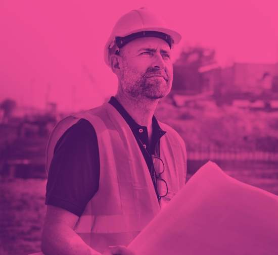 Construction worker looking over plans with building in the background