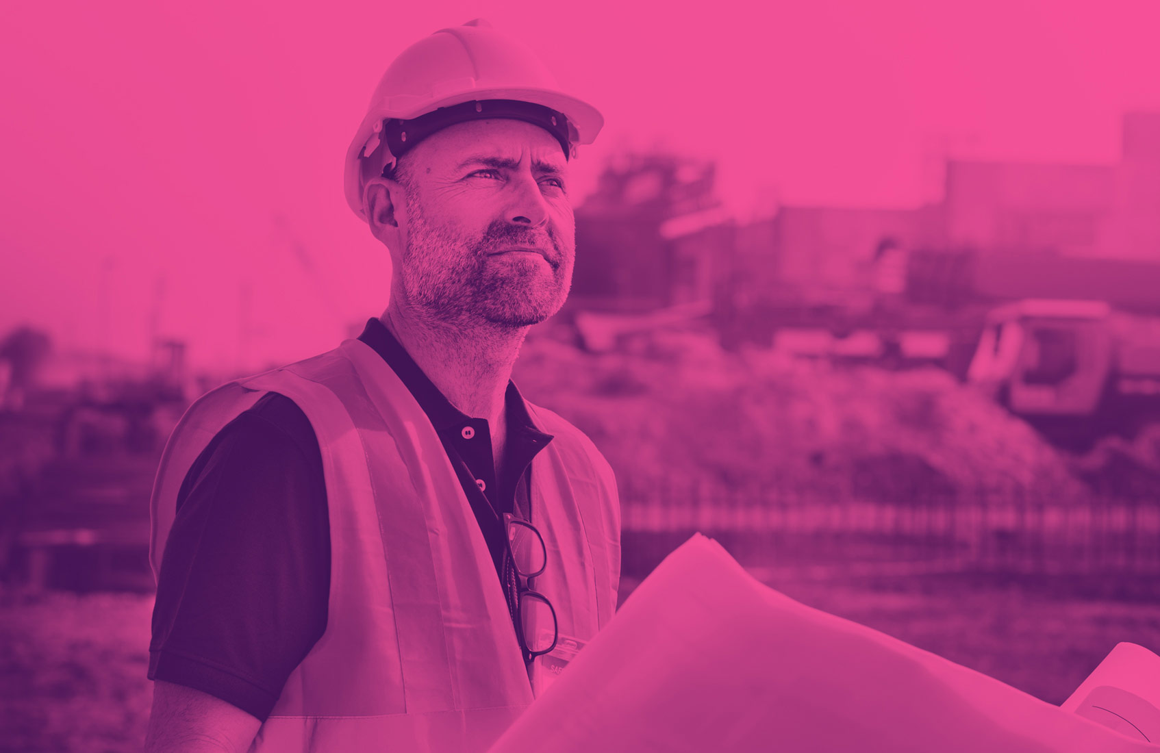 Construction worker looking over plans with building in the background