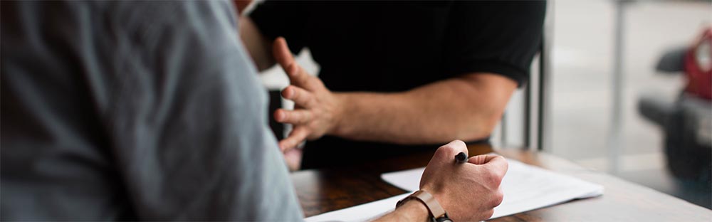 Two people having a discussion on a wood desk