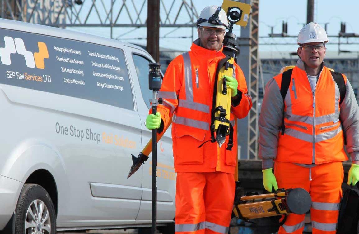 Two men in high visibility clothing holding rail repair equipment  