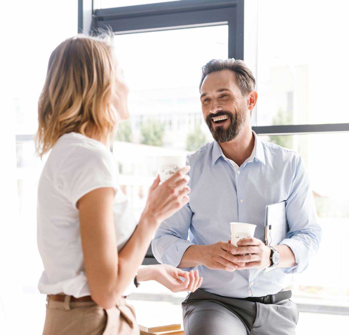 Man leaning on a desk chatting to a woman in an office