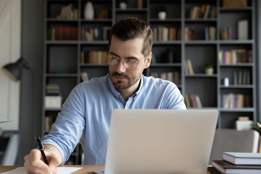 Man working alongside laptop in his study