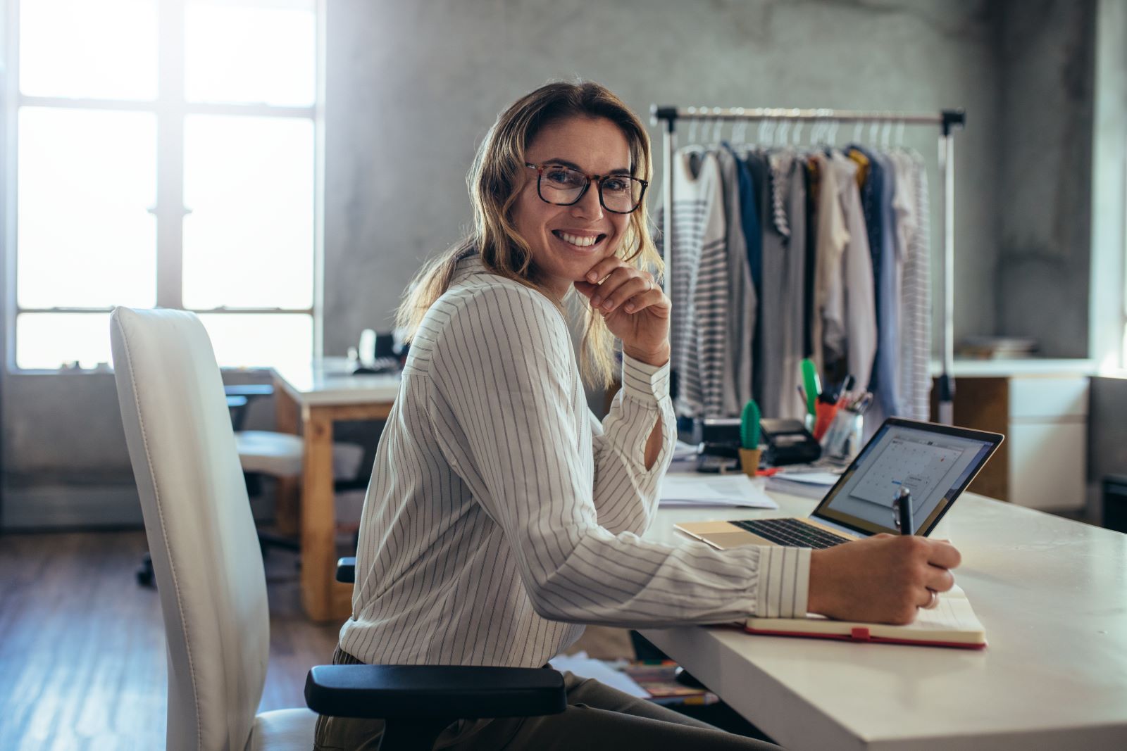 A woman sat at a desk writing on a notepad