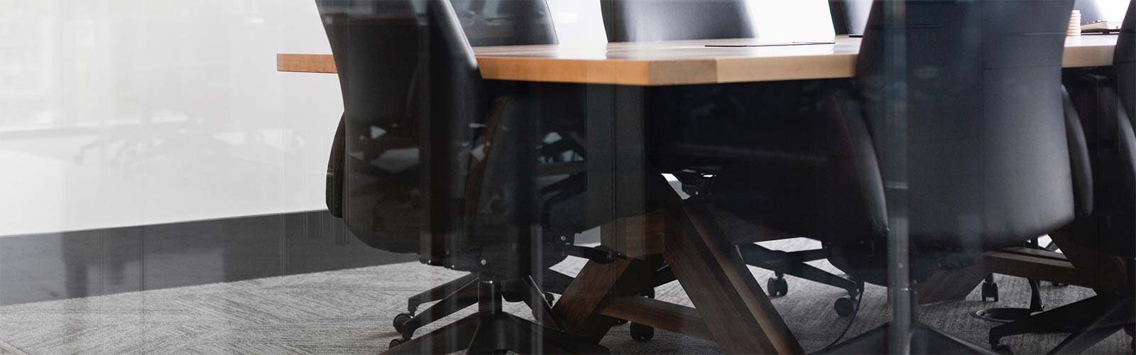 Boardroom desk with black leather chairs surrounding it 