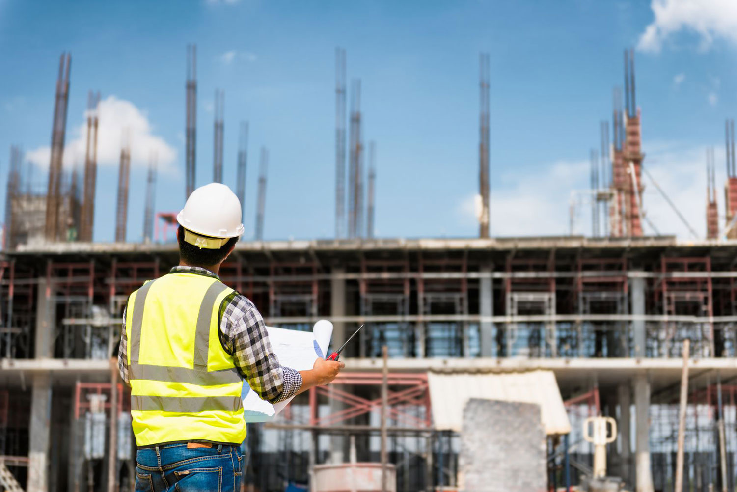 Constructions worker looking over plans in front of the building construction site