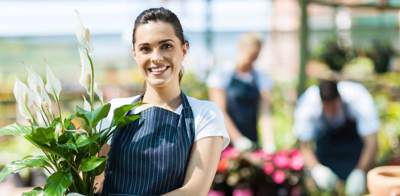 A woman florist holding a bouquet of flowers in front of two other florists