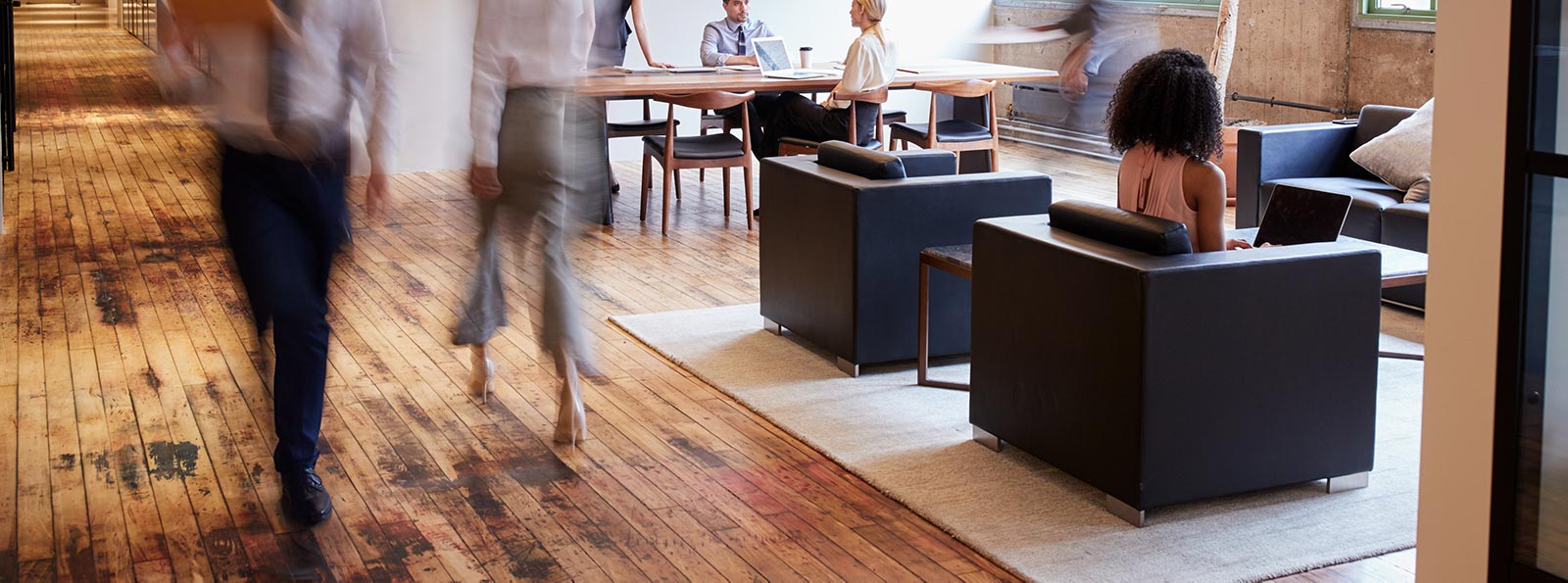 Two people walking through a busy open plan office space