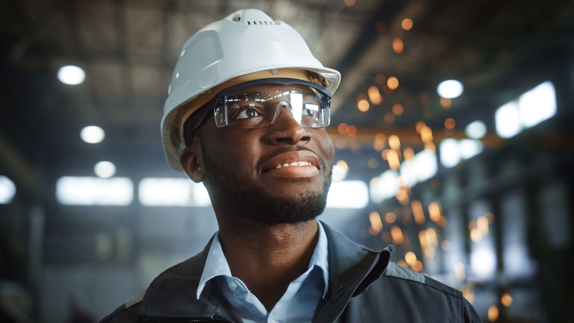 man with hard hat walking through site with sparks