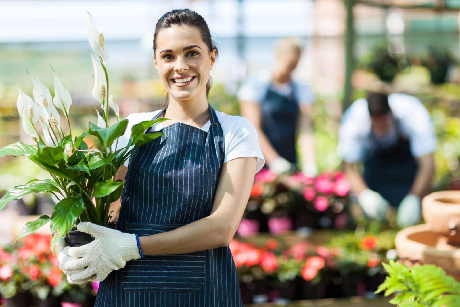 A woman florist holding a bouquet of flowers in front of two other florists