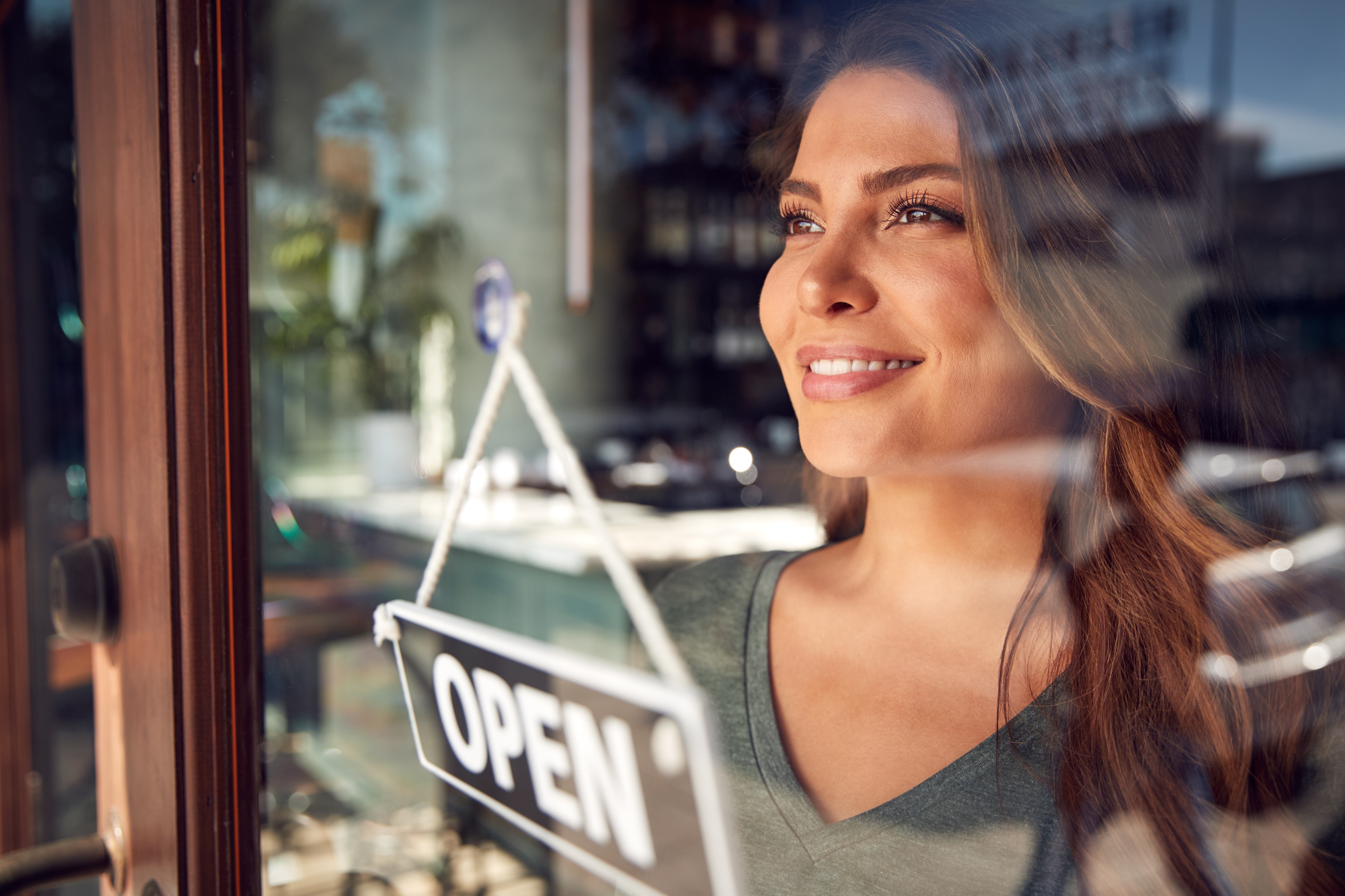 Female open sign looking out of a glass window