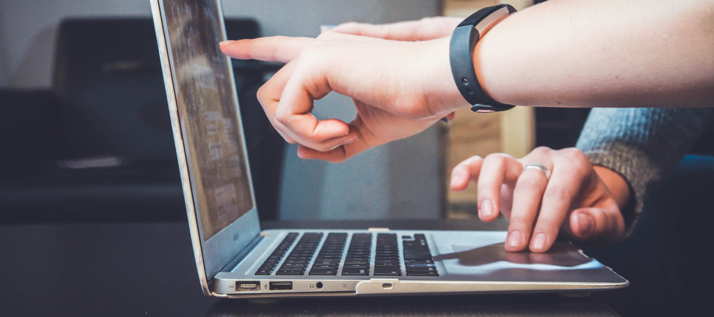 Hands pointing at a laptop screen