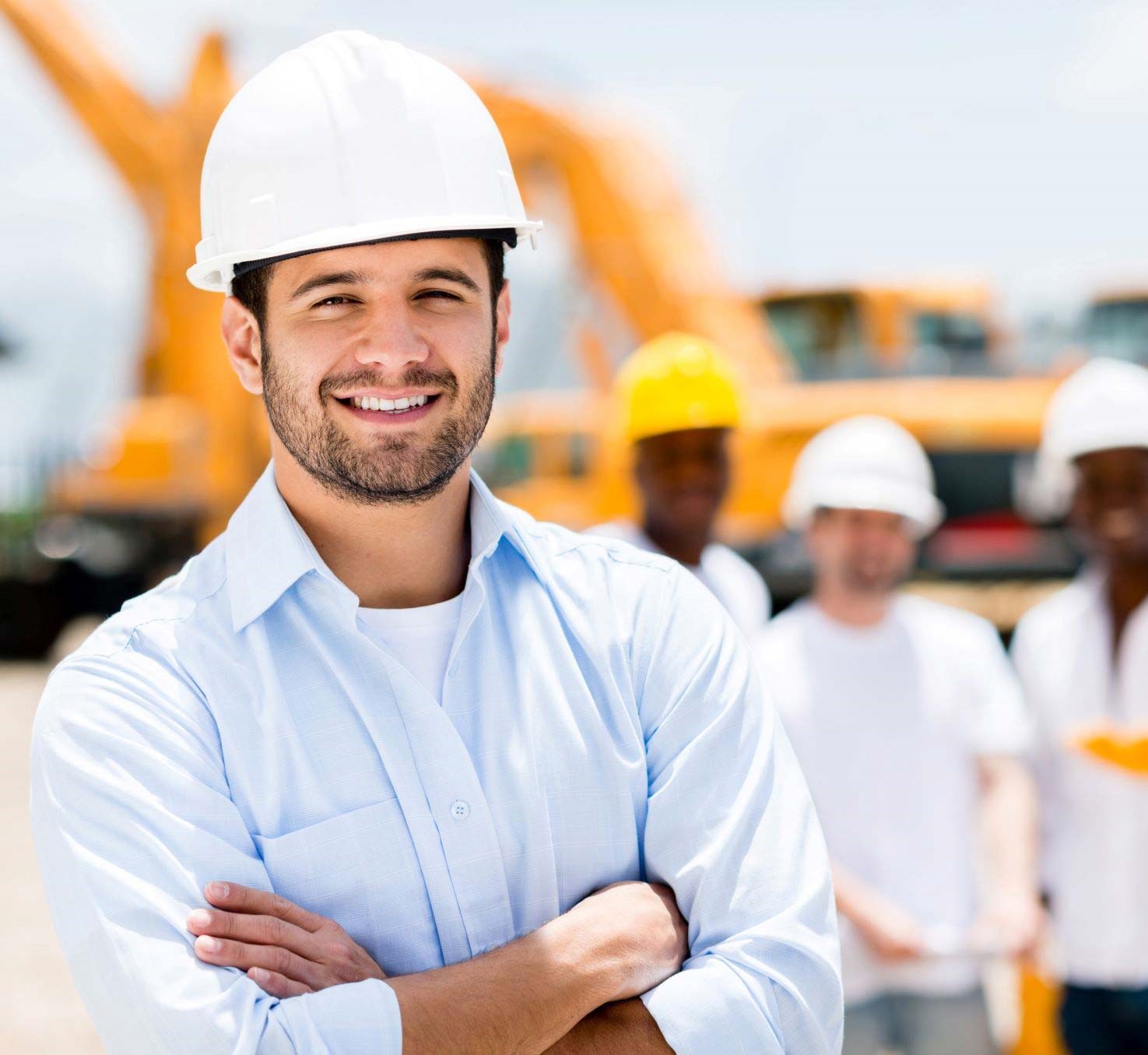 Man in a construction hat and blue shirt stood in front of other construction workers