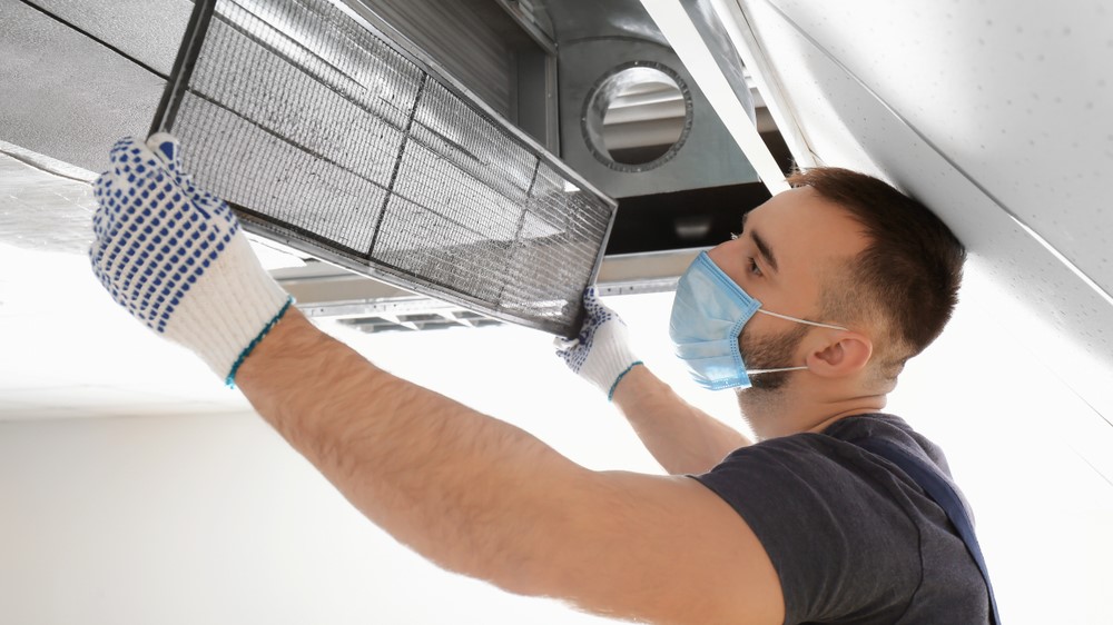 A man holding up a piece of a ventilation machine