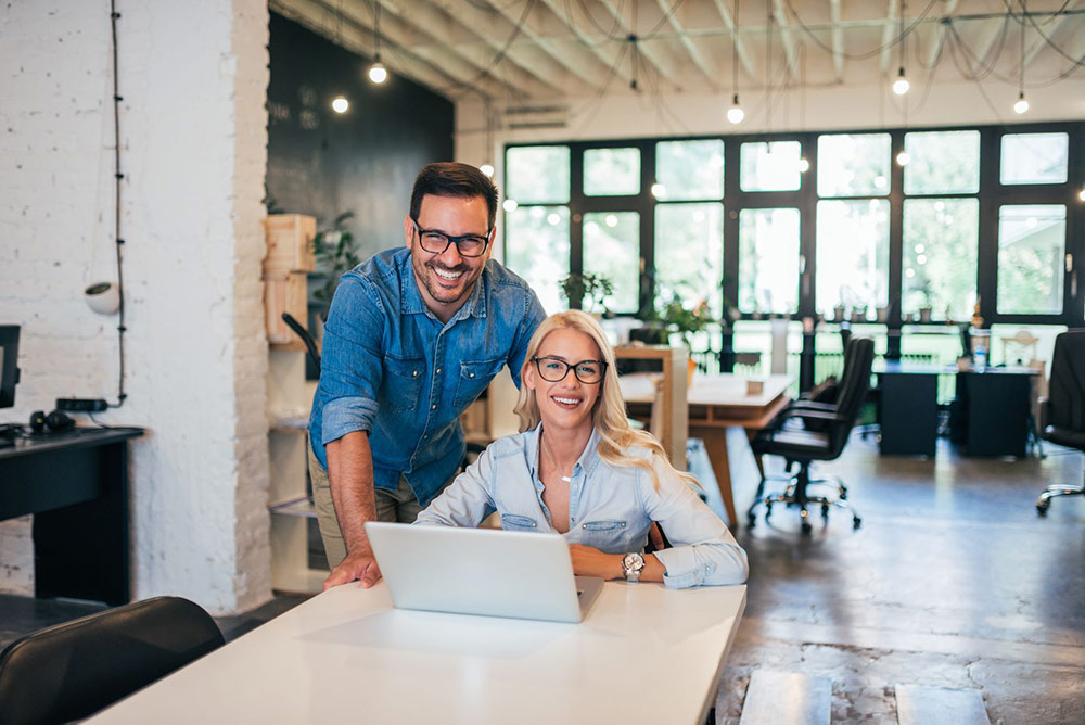 Man and woman smiling at desk with laptop