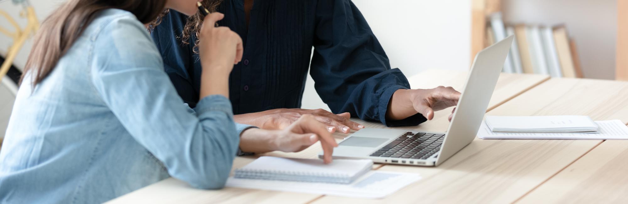 two women pointing at laptop