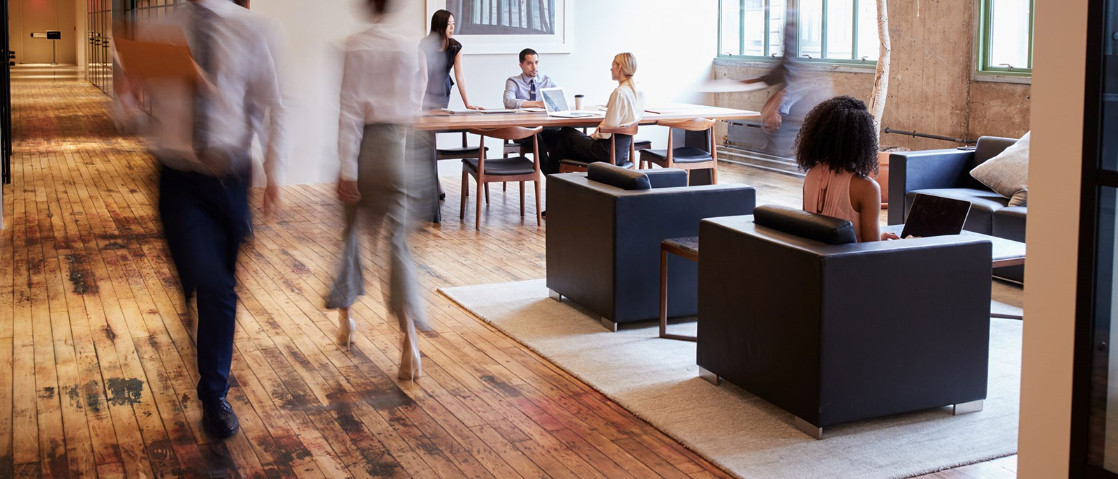 Two people walking through a busy open plan office space