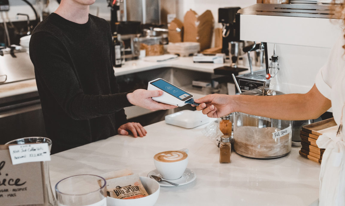 Person using a card machine whilst at the counter of a coffee shop