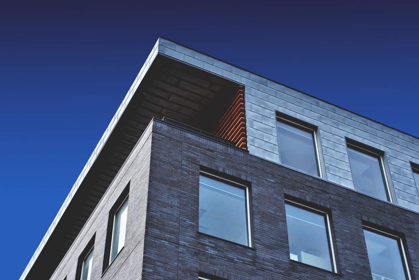 Corner of grey brick building with windows